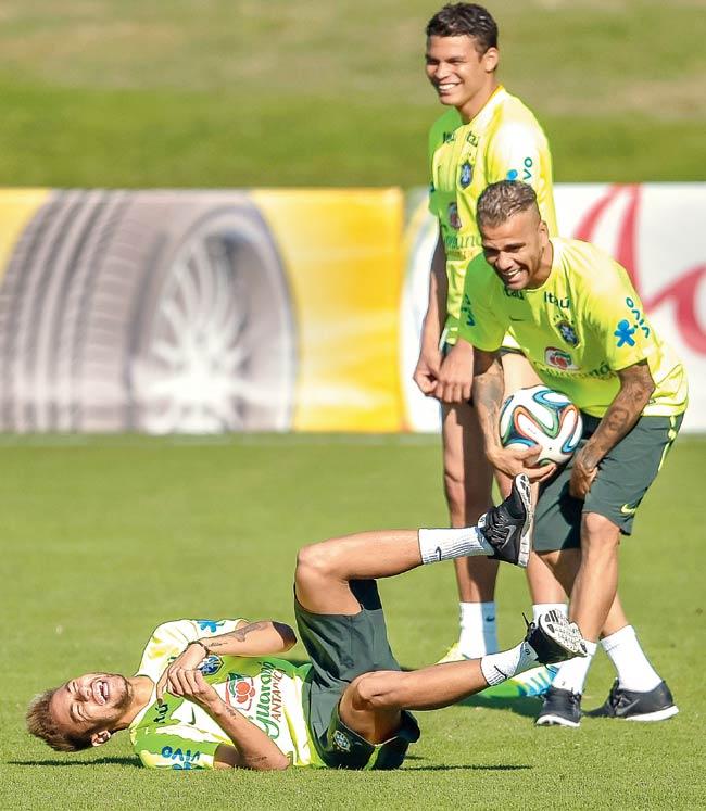 Neymar (left) jokes with Daniel Alves and Thiago Silva (back) during a training session
