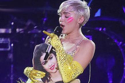 Miley Cyrus throws a photo of Selena Gomez during concert