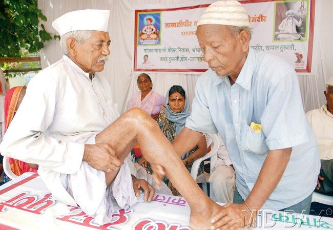 An elderly volunteer from Sakhlipir Talim Mandal massages the tired legs of a warkari. Pics/Mohan PAtil