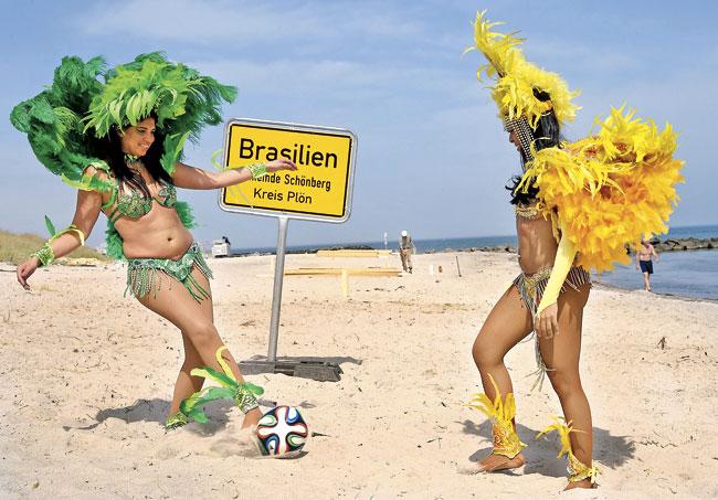 Brazilian dancers Luciana (L) and Simone play football on the beach. Pics/AFP