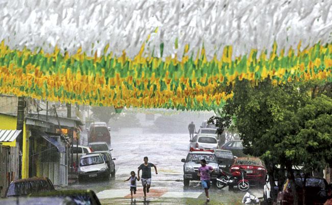 People take cover from the rain under the decorations at Santa Isabel Street in Manaus one of the host cities of the World Cup