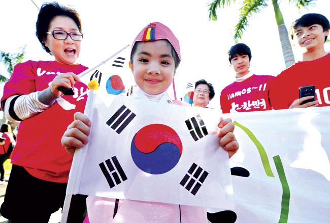 A fan holds the South Korean flag as she welcomes the team at the Bourbon Hotel in Foz da Iguacu