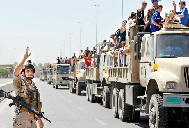 An Iraqi soldier waves out as trucks carrying volunteers to fight along side the Iraqi security forces against Jihadi militants leave a recruitment centre on June 15, 2014 in the Iraqi capital Baghdad. PIC/AFP