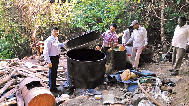 Officials dismantle the implements used to brew booze inside the forest on Saturday morning