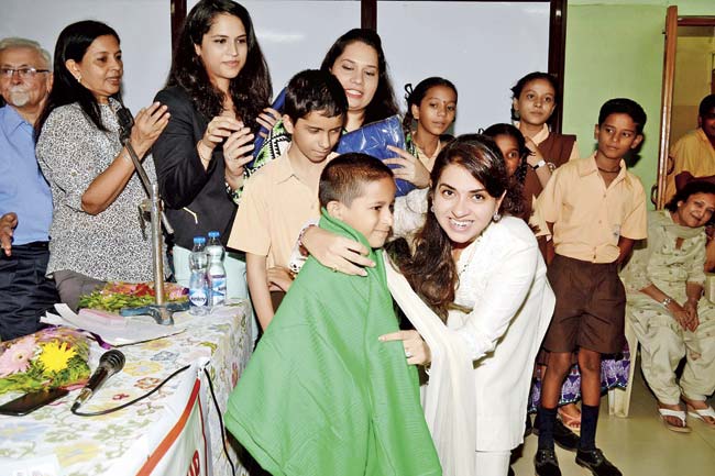Shaina NC distributing mosquito repellent blankets to kids at Girgaon