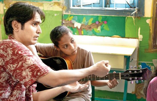 Pakistani musician Hamza Jafri teaches the finer points of playing the guitar to a girl from Lyari in Karachi