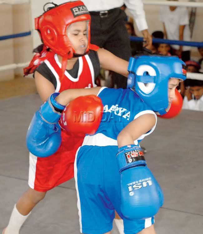 Janhavi Churi (in red) of Mary Immaculate (Borivli) lands a punch on Aarya Dwivedi (blue) of Gopal Sharma Memorial School (Powai) during their U-12 bout in the MSSA Boxing Championships at the District Sports Office Sports Complex in Dharavi yesterday. Pic/Sameer Markande