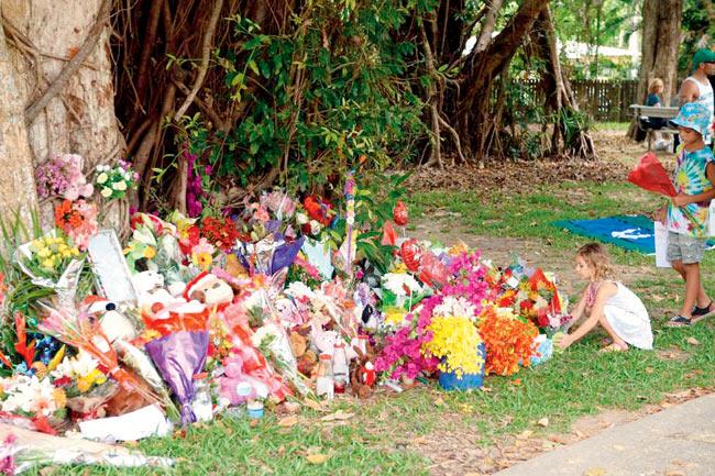 Children lay flowers at the house where eight children ranging from babies to teenagers were found dead in Cairns. Pic/AFP