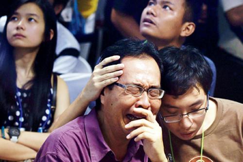 Family members of passengers onboard the missing Malaysian air carrier AirAsia flight QZ8501 react after watching news reports showing an unidentified body floating in the Java sea