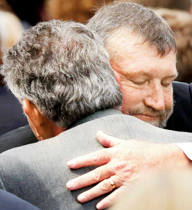 Phillip Hughes father, Gregory (right) hugs a mourner yesterday