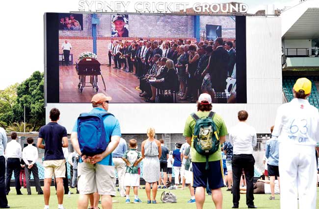 Cricket lovers watch the funeral proceedings of Phillip Hughes on the giant screen at Sydney Cricket Ground yesterday. Pics/AFP, Getty Images