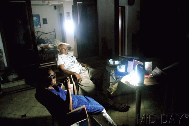 An elderly couple sits beside an emergency light. Residents of many of the flats deemed illegal in Campa Cola compound are celebrating a Black Diwali