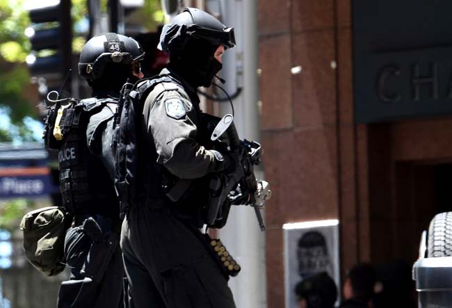 Armed police run toward a cafe in the central business district of Sydney. Hostages were being held inside a cafe with an Islamic flag displayed against a window, according to witnesses and reports. AFP PHOTO