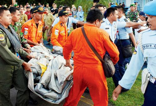 Indonesian Air Force personnel carry airplane parts recovered from the water near the site where Flight 8501 disappeared, at the airbase in Pangkalan Bun, Borneo. 