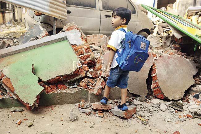 A little boy walks near the wall of his school, which was reduced to rubble. Pics/Khushnum Bhandari
