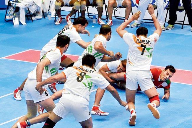 Indian player grabs an Iranian attacker (in red) during the kabaddi gold medal match