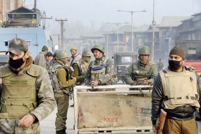 Indian police and paramilitary stand guard during a random search operation in Srinagar on December 6. Militants hurling grenades stormed an army camp in Kashmir on December 5, and killed 11 security officials. Pic/AFP