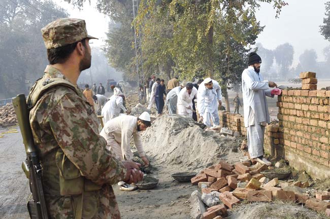 Pakistani labourers build the wall of an army-run school which was attacked by Taliban terrorists in Peshawar. Pic/AFP