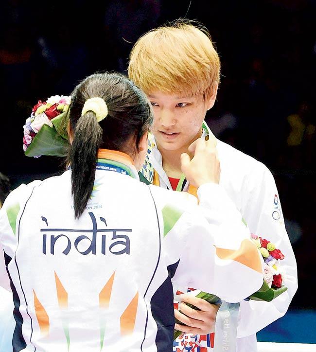 Sarita Devi (left) puts her bronze medal around the neck of Park Ji-na