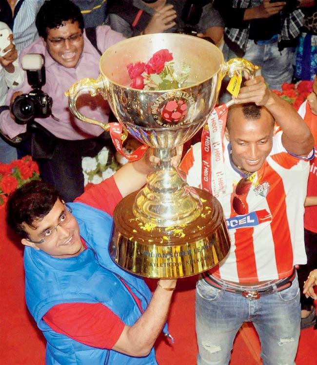 Atletico De Kolkata co-owner Sourav Ganguly poses with the ISL Trophy with his team player Fikru Lemessa