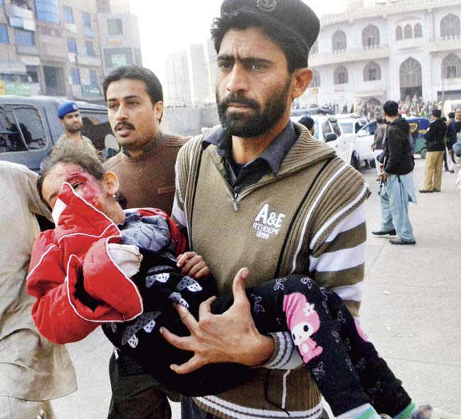 A volunteer carrying an injured student, Army Public School, Peshawar, Pakistan