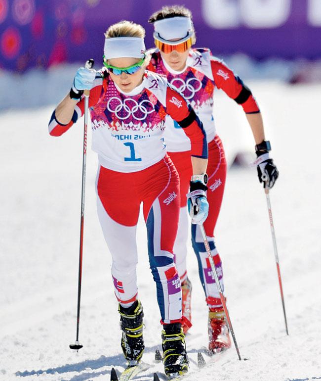 Norwegian skiers compete in the cross-country skiathlon sporting black armbands 