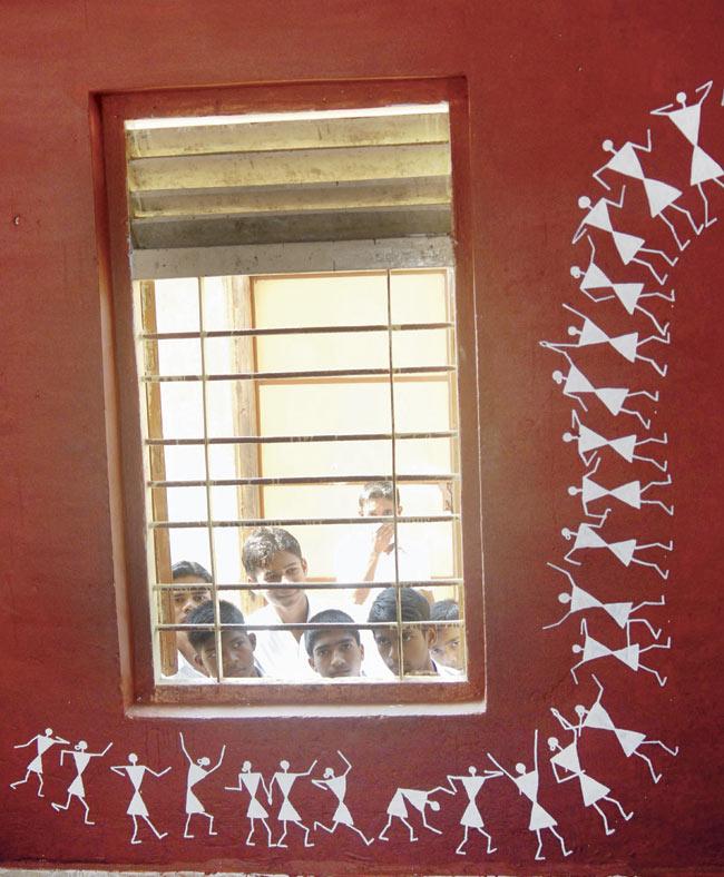 Students look as figures from Warli art are drawn on the walls