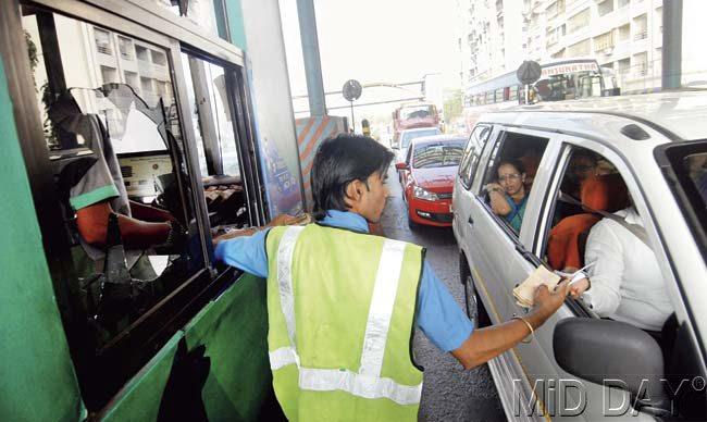 An attendant operates from a broken booth window at Mulund toll Plaza yesterday. Pic/Sameer Markande