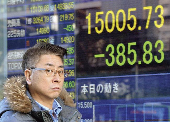 A man checks share prices in Tokyo on Monday, as Japan’s share prices fell 3850.83 points to close at 15,005.73 points at the Tokyo Stock Exchange, following a sell-off on Wall Street and as the dollar sank against the yen on concerns over emerging economies. Pic/AFP