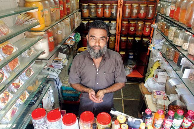 Owner Naeem Jaffer stands amid shelves neatly lined with a variety of pickles and masalas
