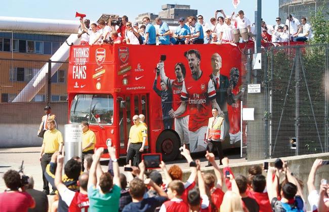 Fans catch a glimpse of their favourite players during the Arsenal FA Cup victory parade in London yesterday. Pic/Getty Images