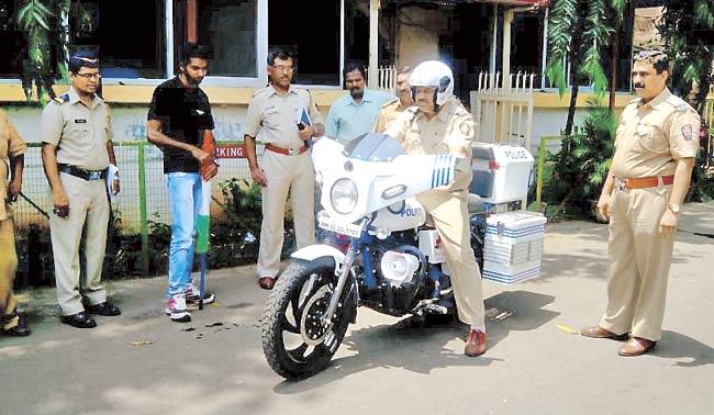 Cops take the bike for a test run; they told Gabriel Zuzarte (in black) that the bike’s weighty back equipped with laptop and printer boxes was making it wobbly to ride