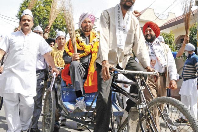 Aam Aadmi Party (AAP) candidate for the Amritsar parliamentary seat Daljit Singh (C) sits on a rickshaw as he heads to file his nomination papers at the deputy commissioner