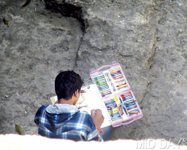 Art materials on display as a young man begins his work in the Jogeshwari Caves