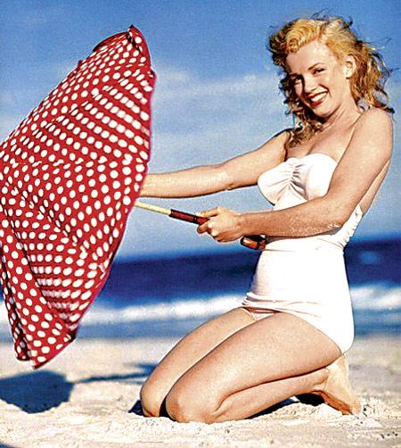 Marilyn Monroe on the beach in a one piece with the wind attempting to blow her red polka dot umbrella away, is classy, fun and whimsical they say