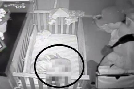 Burglar looks over sleeping infant