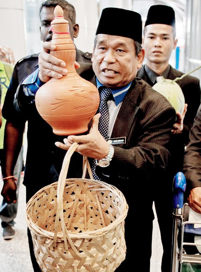 abracadabra: Ibrahim Mat Zin along with his assistants used bamboos as binocular and looked into a fish trap hook to “locate” the missing plane and found it in the land of elves. He also waved the coconuts to set the plane free from there. pics/afp