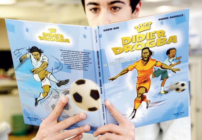 A young enthusiast in Paris reads a comic book in which Drogba is the main character. Pic/AFP