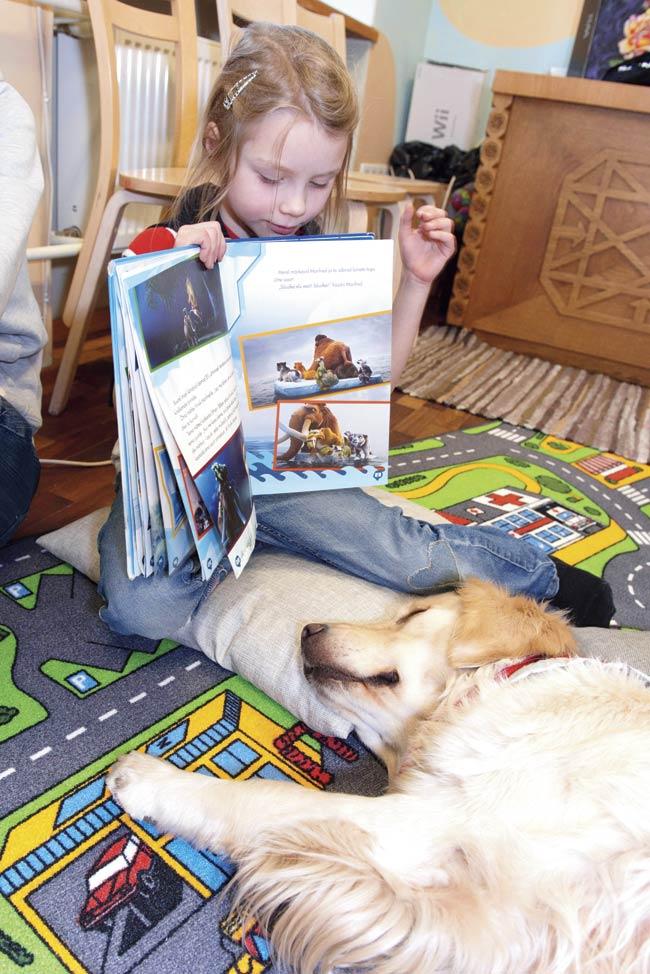 Tentel, the furry hound, falls asleep while six-year-old Ingrid reads to the dog at the library in Tartu. Pic/AFP