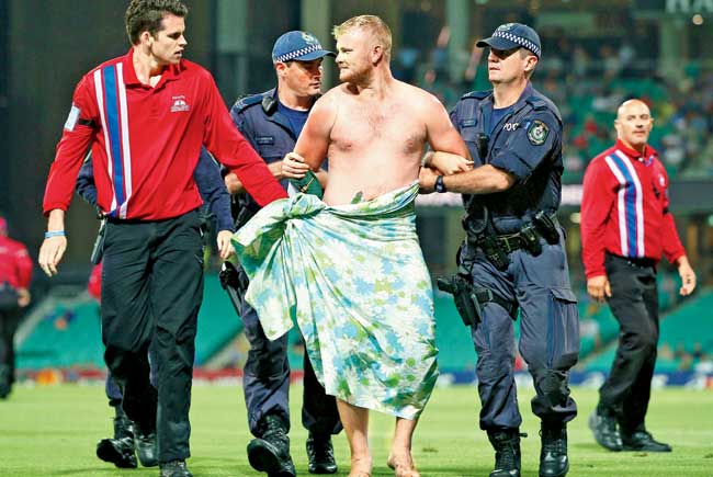 Security officials grab a streaker during the fifth ODI at Sydney yesterday