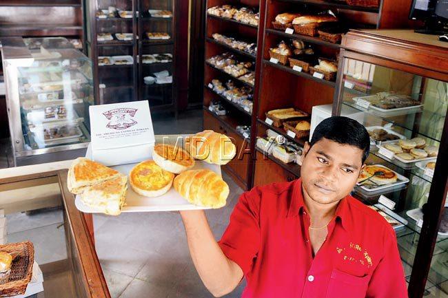 Babu, of the American Express Bakery (AEB) in Bandra, poses with the bakery’s favourite baked goodies. He has been with AEB for the last 16 years. Pic/Nimesh Dave