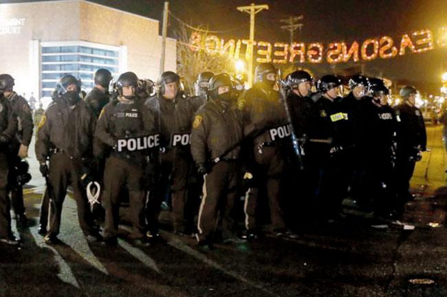 Police stand guard as protesters gather in front of Ferguson Police Department on  November 28, 2014. Pic/AP