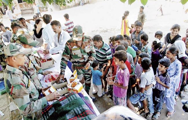 Flood-affected people receive food items at an Indian Army relief camp in Jammu on Monday