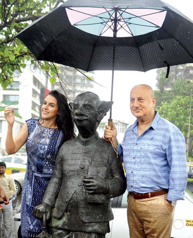 Neha Dhupia (l) and Anupam Kher pose for a photograph during a promotional event for the forthcoming film Ekkees Toppon Ki Salaami alongside the Common Man Statue. Pic/AFP