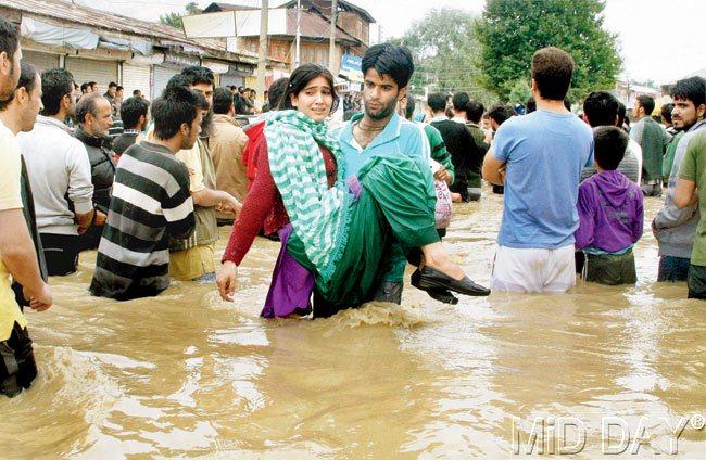 A volunteer rescues a young woman caught in the flood in Chattabal area of Srinagar
