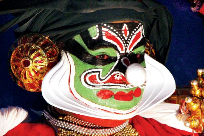 A Kathakali artiste, whose eyes are red from all the make-up, strikes a pose