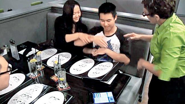 An attendant interacts with customers who attempt to use sign language to place an order at Signs