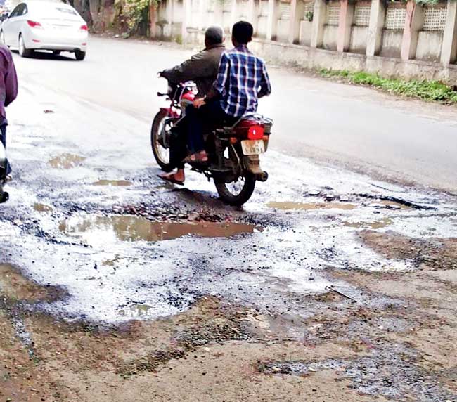 Weaving through pits: The potholes force drivers to move slowly, causing traffic jams during peak hours