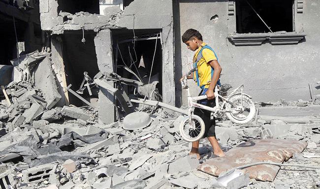 A Palestinian boy carries a bicycle from a wrecked building, which was hit by an Israeli strike, in Rafah, in the southern Gaza Strip yesterday. Pic/AFP