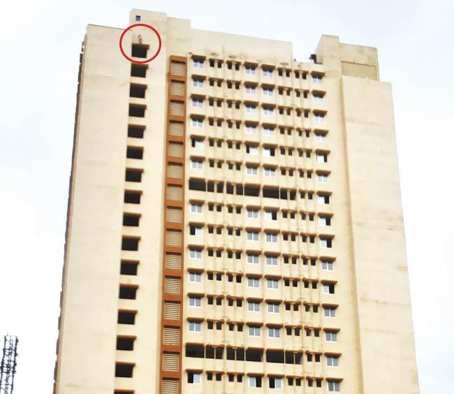 Ajay Babu Dhothre (circled) atop the 22-storey building yesterday